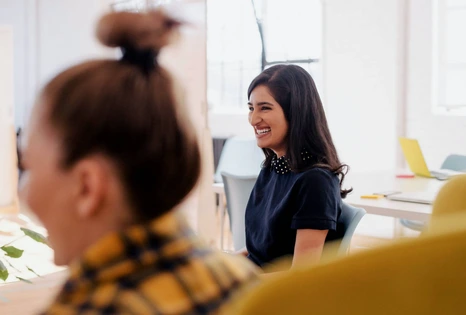 Photo d'une femme souriante en réunion d'entreprise dans une salle lumineuse